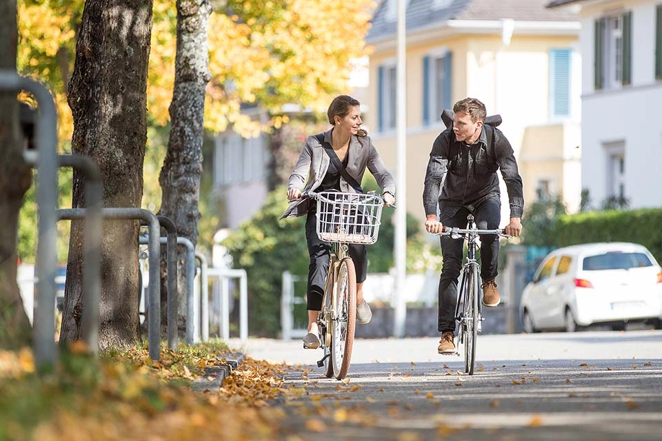 Zwei Radfahrer:innen fahren im Herbst zusammen Fahrrad